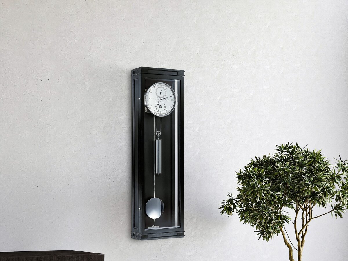 Hermle regulateur in zwart aan een lichte muur